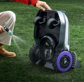 Das Bild zeigt einen Anthbot N8 Mähroboter, der von einem Mann mit einem Gartenschlauch vorsichtig gewaschen wird.