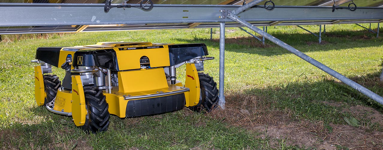 Auf diesem Bild ist der Spider 2SGS EFI Super Low zu sehen, der unter einer Solarpanel-Anlage hindurchfährt.