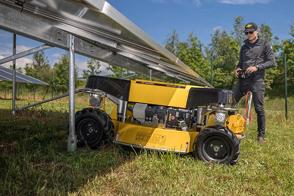 Auf diesem Bild ist der Spider 2SGS EFI Super Low zu sehen, der unter einer Solarpanel-Anlage hindurchfährt. Daneben steht die Bedienperson mit einer Fernbedienung. Auf diesem Bild ist der Spider 2SGS EFI Super Low zu sehen, der unter einer Solarpanel-Anlage hindurchfährt. Daneben steht die Bedienperson mit einer Fernbedienung.